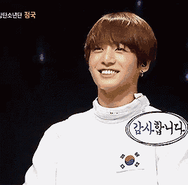 a young man wearing a white shirt with korean writing on it smiles