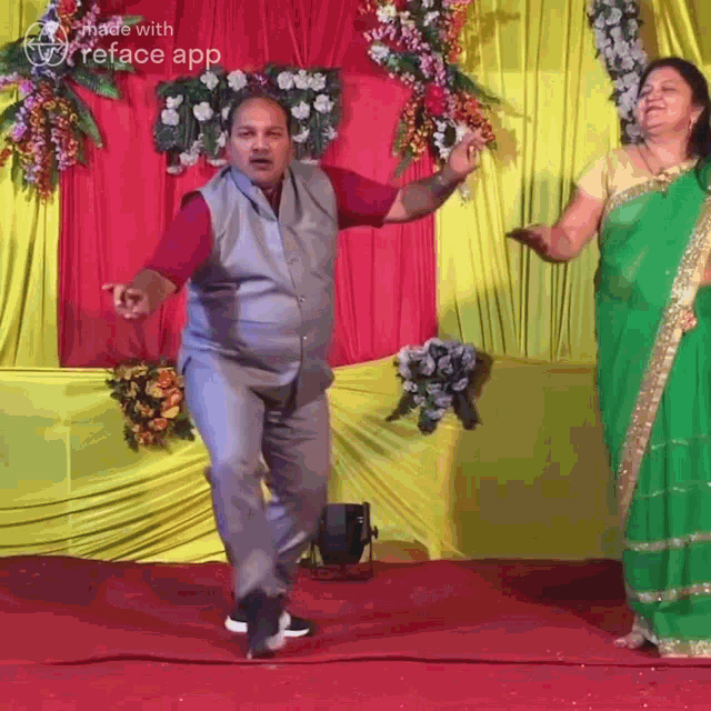 a man and a woman are dancing on a stage with flowers in the background