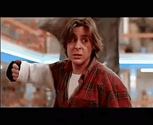 a man in a plaid shirt is pointing his finger at someone .