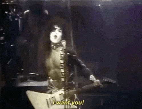 a man singing into a microphone while playing a guitar and says i want you