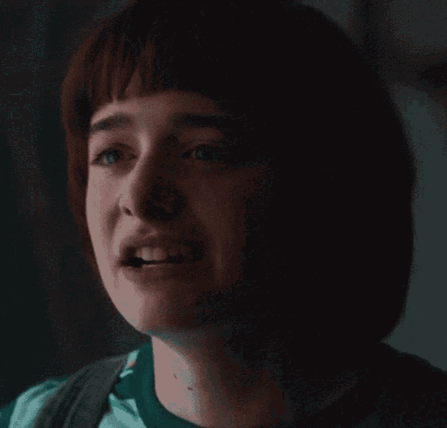 a close up of a person 's face with a green shirt on