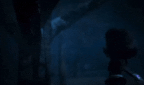 a person is standing in a dark room with a blue light coming out of the ceiling .