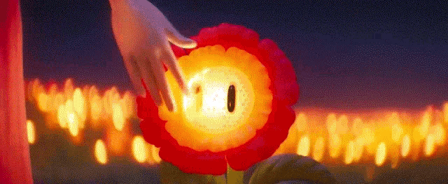 a person is touching a red flower with a candle in the background .