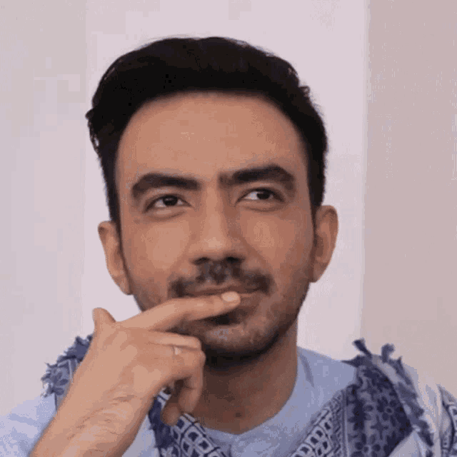 a man with a beard and a scarf around his neck is thinking