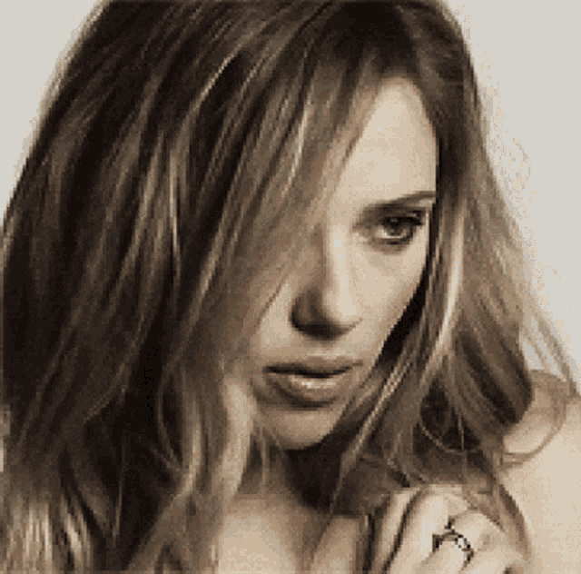 a close up of a woman 's face with a ring in her finger