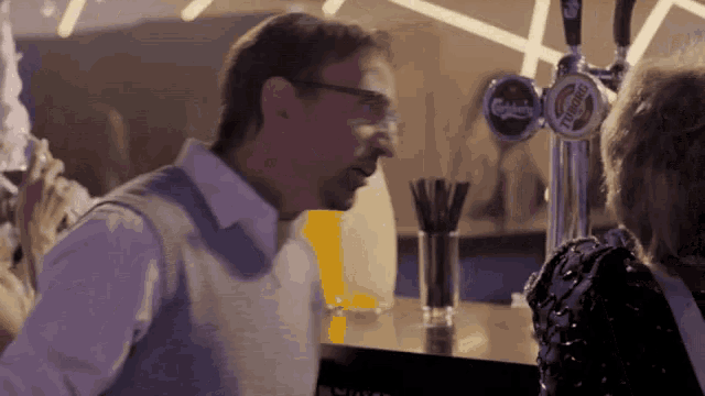 a man talking to a woman at a bar with a carlsberg beer tap