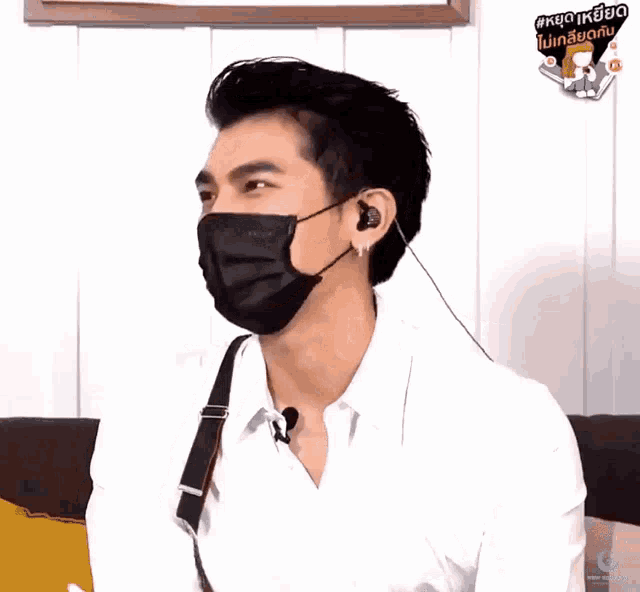 a man wearing a mask and ear buds has a sticker on his shirt that says ' knock knock '