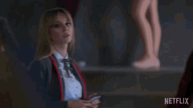 a woman in a suit is holding a cell phone in front of a netflix sign