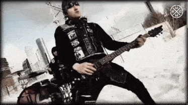 a man is playing a guitar in front of a sign that says ' x '