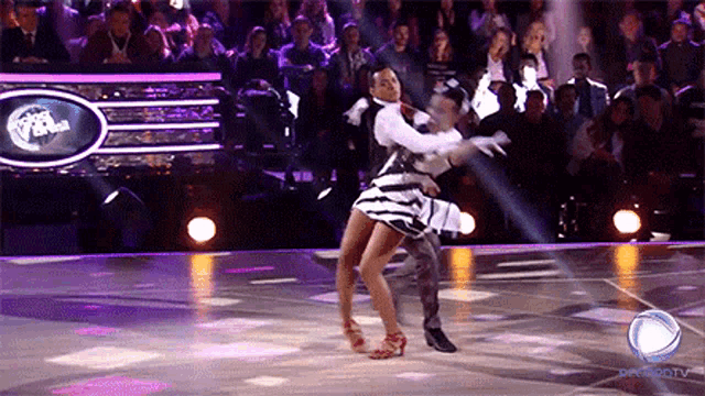 a couple of people are dancing on a dance floor in front of a sign that says ' dancing with the stars ' on it
