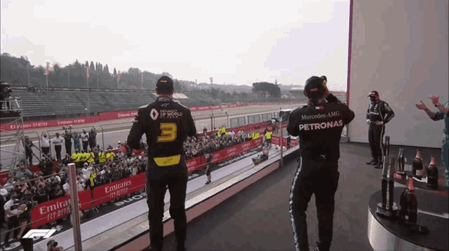 a man wearing a petronas shirt stands on a podium