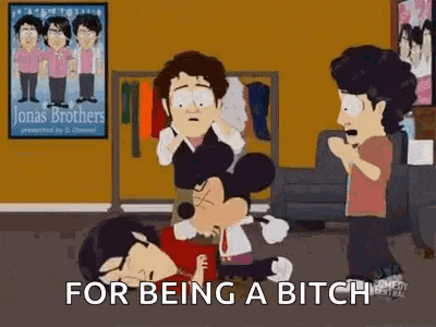 a group of people are standing around a mickey mouse cartoon character in a room .