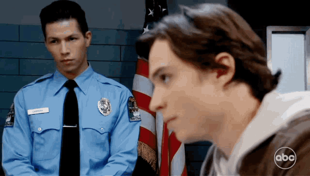 a police officer named johnson stands next to a man in front of an american flag