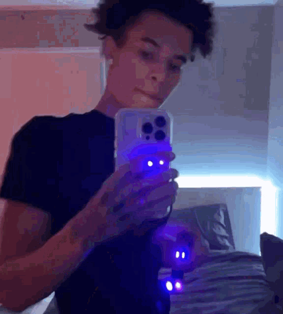 a young man is taking a picture of himself in a mirror with a blue light .