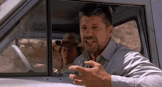 a man in a cowboy hat is looking out the window of a car