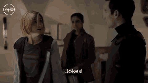 a man and a woman are standing next to each other in a dark room and talking to each other .