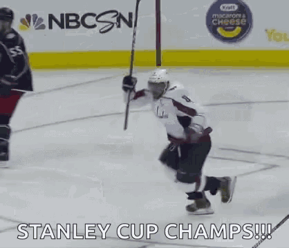 a hockey player is kneeling down on the ice while holding a stick .