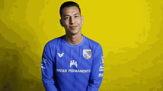 a man wearing a kaiser permanente jersey stands in front of a yellow background