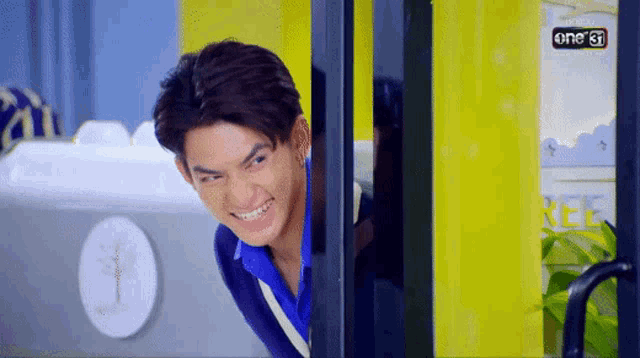 a young man is making a funny face while peeking out of a doorway .