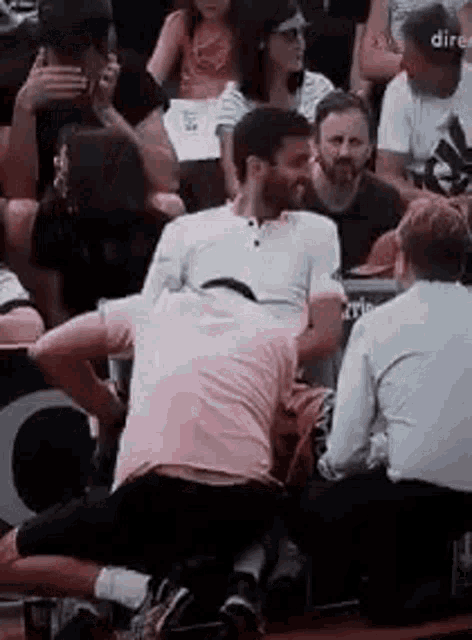 a group of people are sitting in a stadium watching a game and one of them is kneeling down .