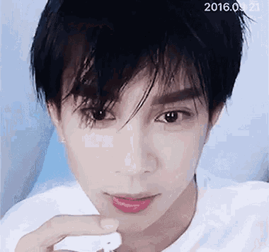 a close up of a young man 's face with a white t-shirt on .