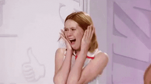a woman is covering her face with her hands while screaming .