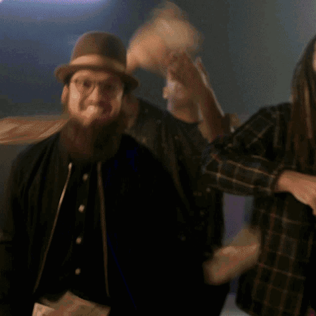 a man with a beard wearing a hat is dancing in a dark room
