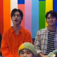 a group of young men are standing in front of a colorful striped wall .