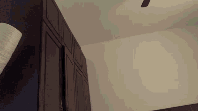 a blurry picture of a person laying on a bed with a ceiling fan in the background .