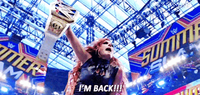 a woman is holding a wrestling championship belt and saying " i 'm back "