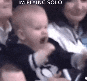a baby is crying in a crowd of people .