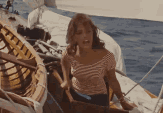 a woman in a striped shirt is sitting in a boat in the ocean .