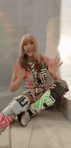 a woman in a colorful outfit is sitting on the floor with her hands up