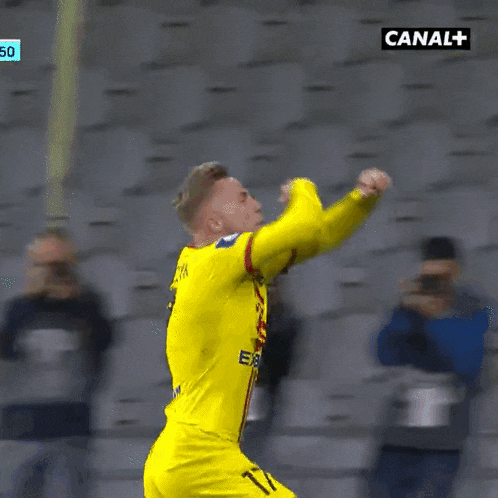 a man in a yellow jersey is being thrown in the air by a man in a black jacket with canal + written on it