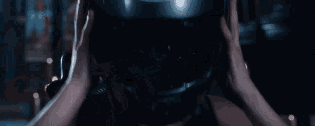 a woman is standing in a dark room with candles in the background .