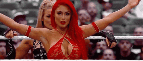 a woman with red hair is standing next to another woman in a wrestling ring .
