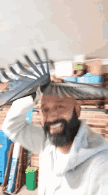 a man with a beard is holding a rake over his head and smiling