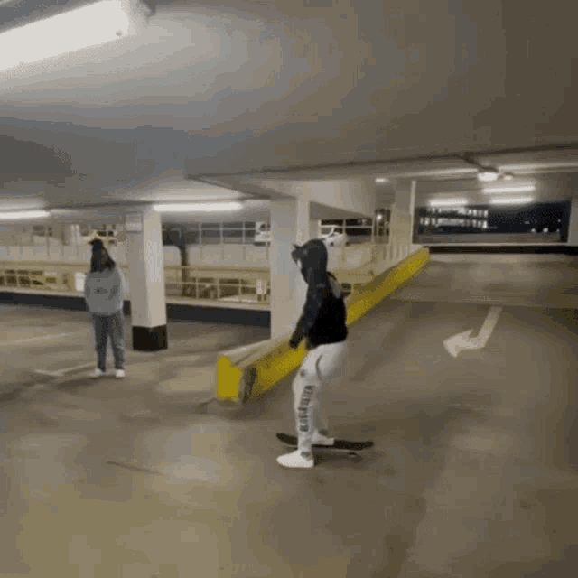 a person riding a skateboard in a parking garage wearing a hoodie that says wildfire