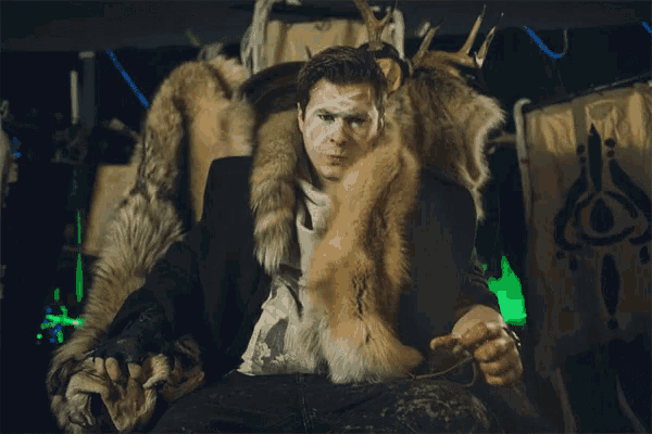a man with white paint on his face has a fur coat around his neck