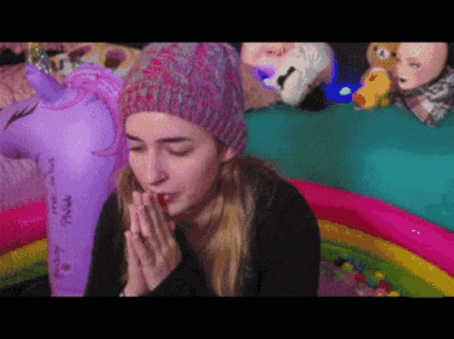 a woman wearing a pink hat is praying in front of a unicorn float