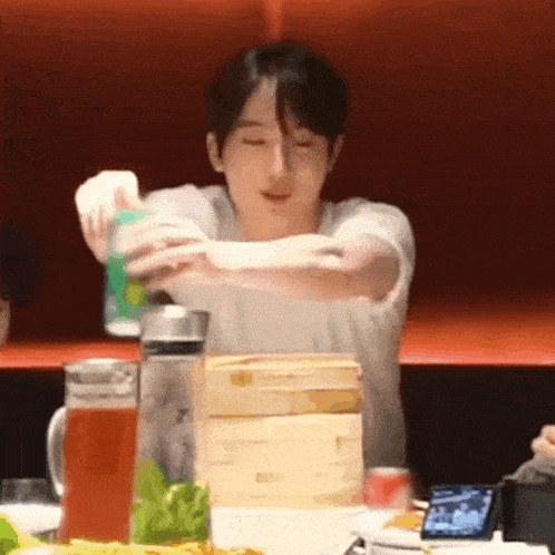 a man is pouring a can of soda into a pitcher at a table .