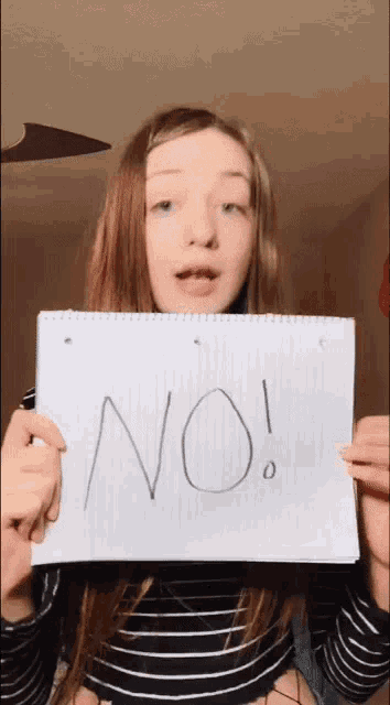 a girl is holding up a piece of paper that says no