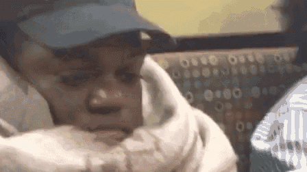 a close up of a person wearing a hat and holding a blanket .