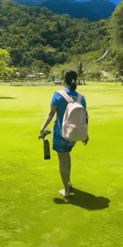 a woman wearing a blue shirt that says sky is walking on a green field