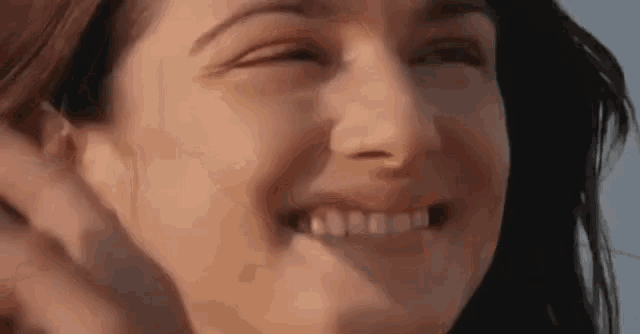 a close up of a woman 's face smiling with her eyes closed and her mouth open .