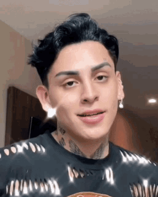 a young man with a tattoo on his arm is wearing a black shirt and earring .