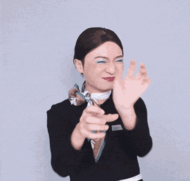 a woman in a suit and scarf is making a gesture with her hands
