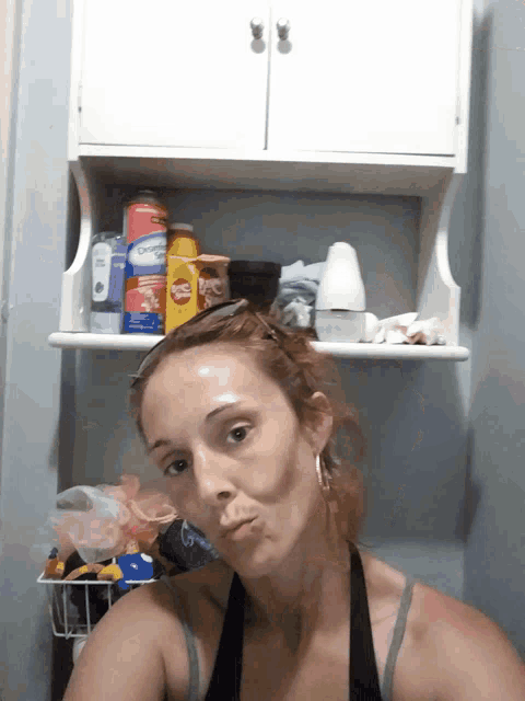 a woman making a funny face in front of a shelf with a can of cheerios
