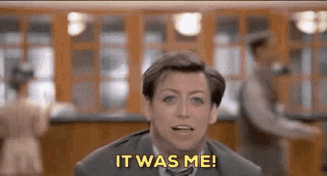a man in a suit and tie is saying `` it was me '' while standing in a room .