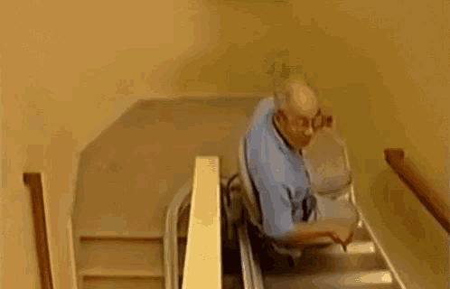 an elderly man is using a stair lift to go up the stairs .